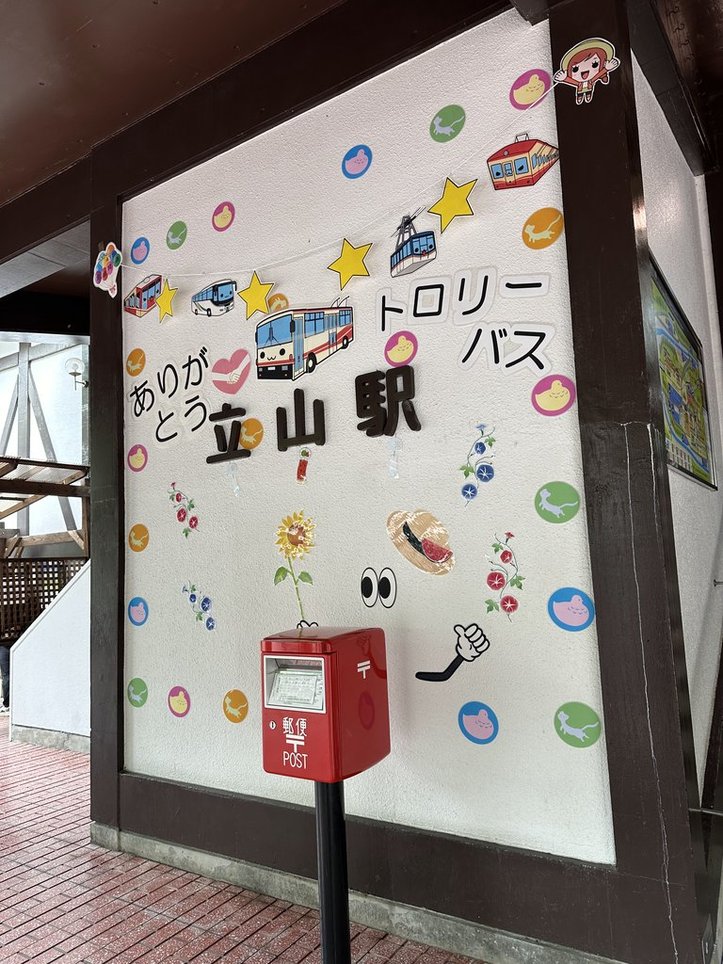 立山駅と書かれた縦長の壁に「ありがとうトロリーバス」の文字とともに立山黒部アルペンルートの乗り物のイラストが貼られている。中央の「立山駅」の上の部分にはもちろんトロリーバスのイラスト。