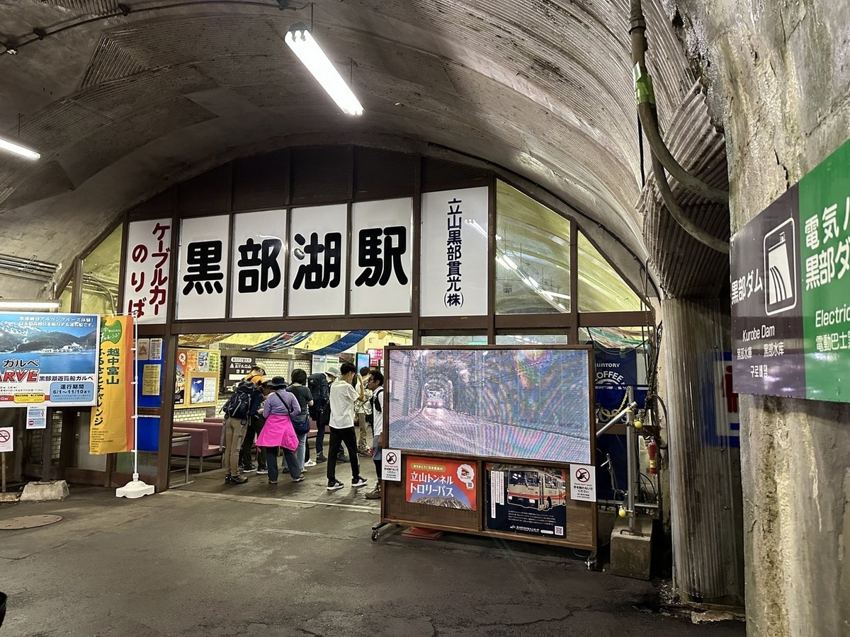アーチ状の天井の空間にガラスの仕切りがあり、一部が開いて通れるようになっている。上には「ケーブルカーのりば 黒部湖駅 立山黒部貫光(株)」と書かれている