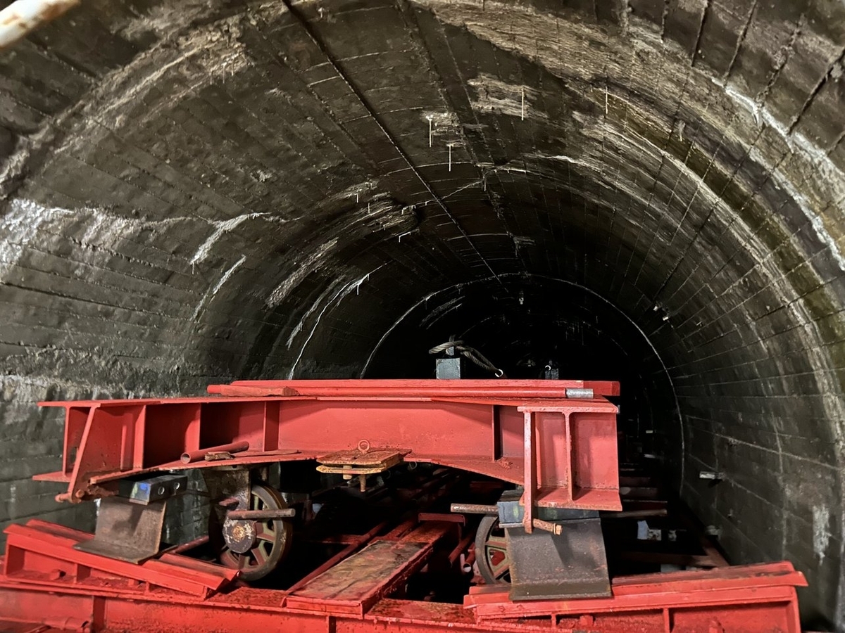 幅の狭いトンネルめいっぱいに赤い鉄骨とタイヤとロープを組み合わせた機械のようなものが置かれている