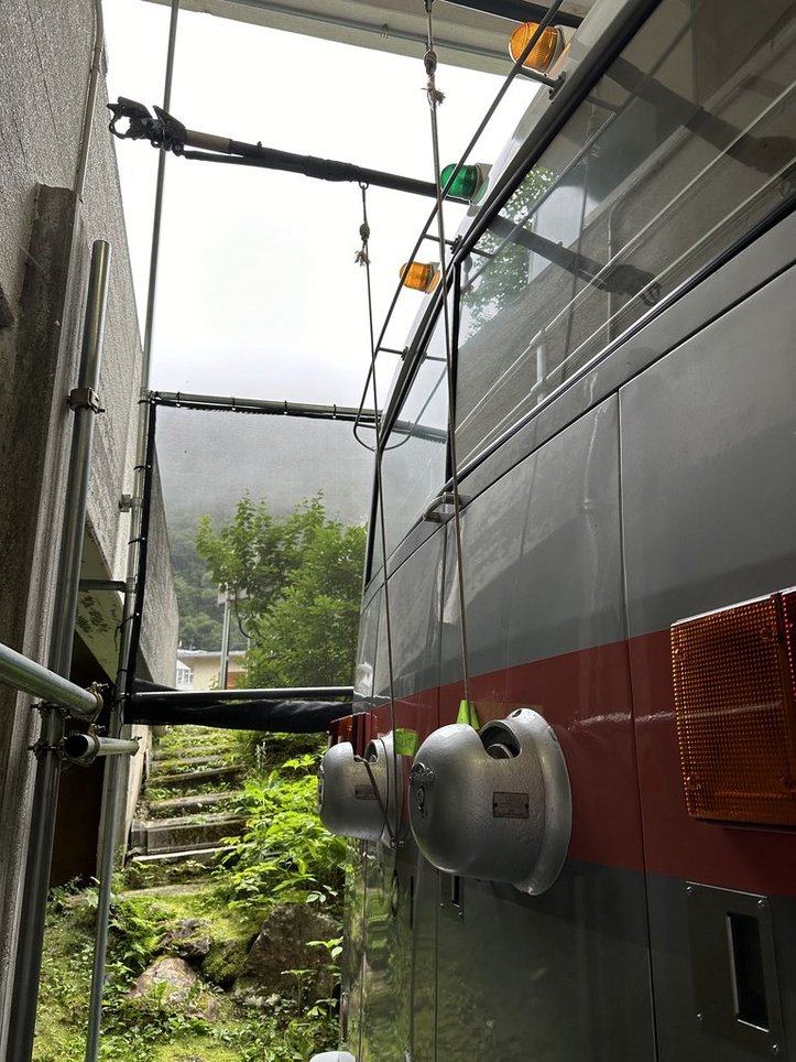 バス後部。屋根の左右から棒のようなものが伸びており、そこにロープが繋がれている。ロープは下に伸び、ボディに取り付けられた丸い器具に収納されている。