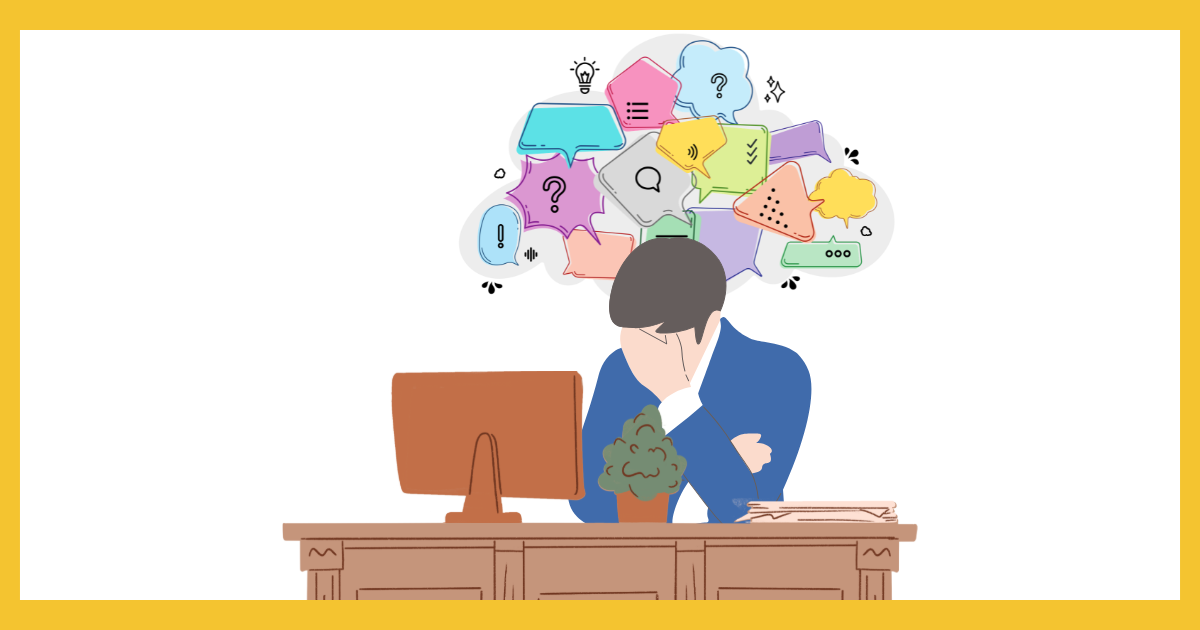 パソコンの前で頭を抱えて落ち込むビジネスパーソンのイラスト。頭上には、整理されない様々な不安や思考を表す、多くのカラフルな吹き出しが浮かんでいる。