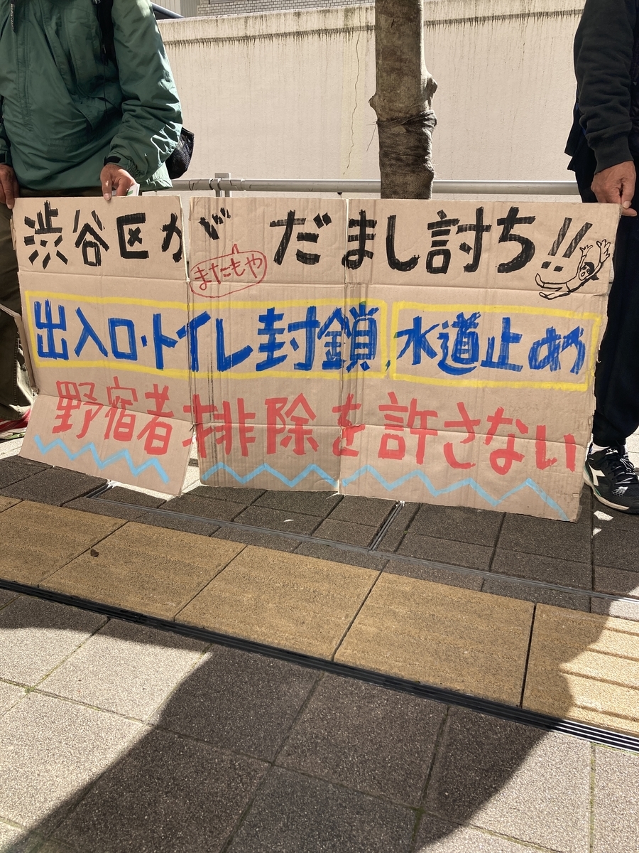 「渋谷区がまたもやだまし討ち！！　出入口・トイレ封鎖　水道止め　野宿者排除を許さない」と書かれたプラカード