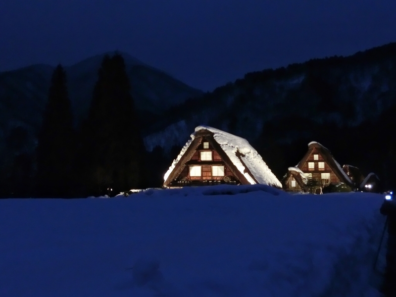 ライトアップされた白川郷のかやぶきの家。屋根には雪が積もっている