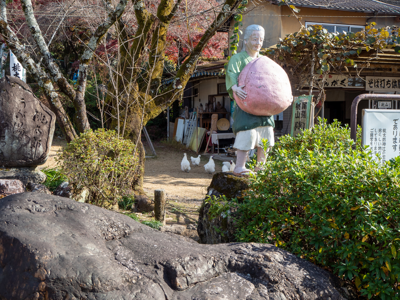 犬山市にある桃太郎神社にある桃太郎のおばあさんの人形。川へ洗濯に行ったおばあさんが両手で大きな桃を持っている