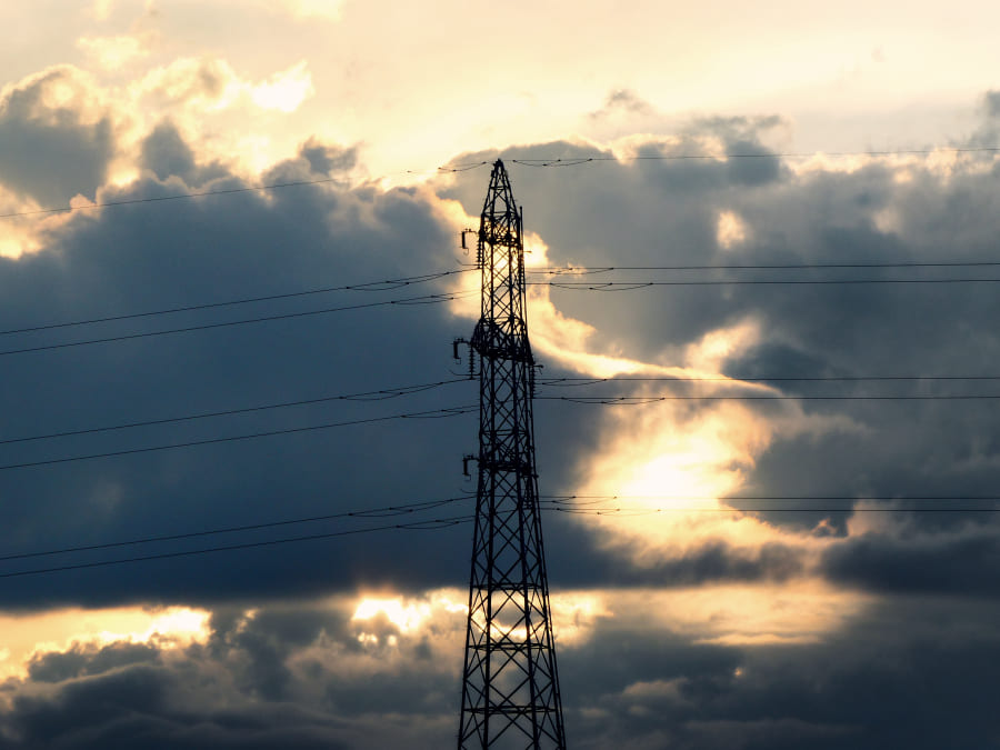 写真撮影 分厚い雲ににじむ夕日に照らされた送電塔