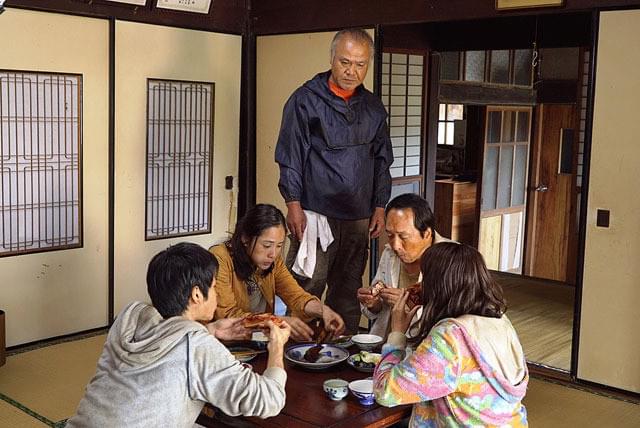 養豚農家の田中の家で食事する鈴木一家