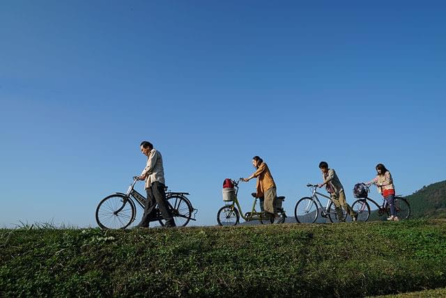 田舎道を自転車で進む鈴木一家の画像