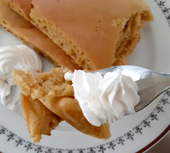 ホイップクリームとホットケーキをフォークで食べる写真