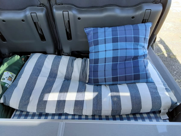 クルマの荷台にクッションと長座布団を敷いて昼寝