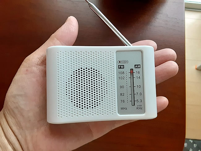 手のひらに乗せた小型携帯ラジオ
