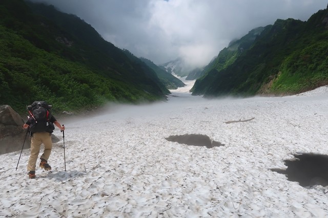 雪渓のクラックを避けて歩く登山者