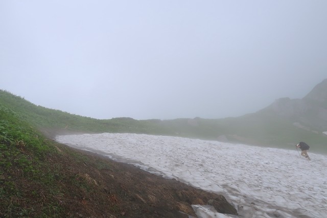 草付きの広場を直登する登山者