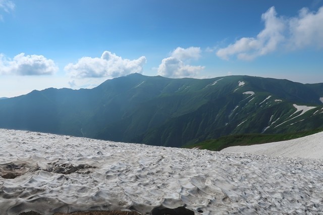 雪渓越しの飯豊山の山頂とダイグラ尾根