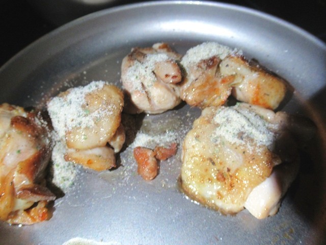 焼きあがった鶏肉に味付け調味料を振りかけた様子