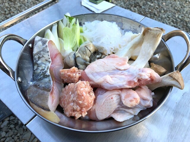 キャンプで鍋の具材を入れている様子