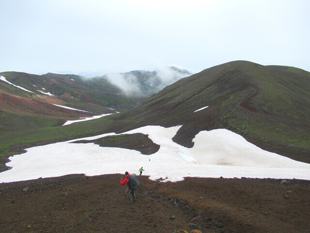広大な残雪の上に大雪山の登山コースがある