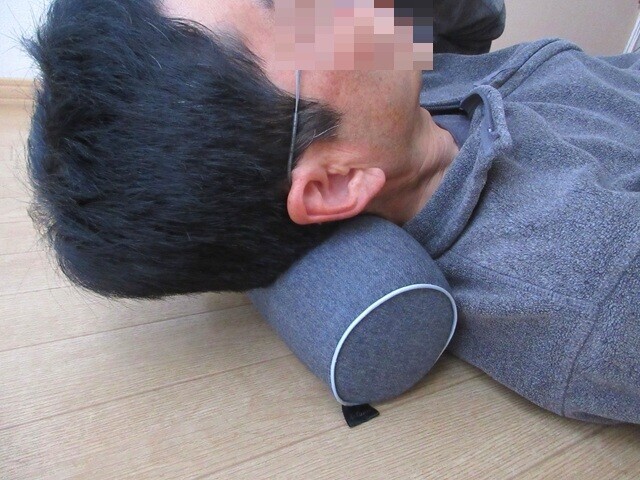 ネックピローを使って首のストレッチを行っている様子