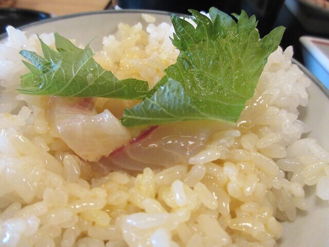 鯛めしをご飯の上にかけて食べている様子
