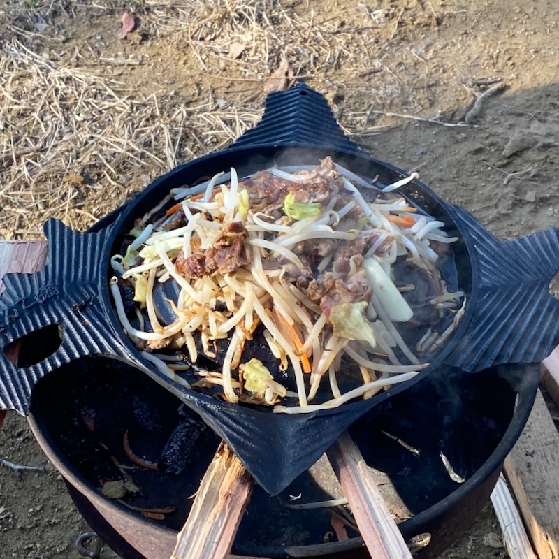 ジンギスカン鍋でラム肉と野菜を焼く焚き火キャンプ料理