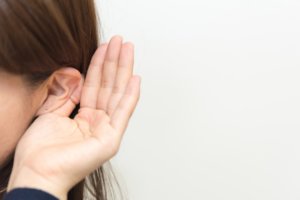 耳に手を当て聞き返す女性