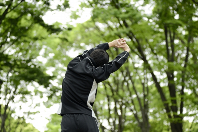 公園でセルフストレッチをする男性