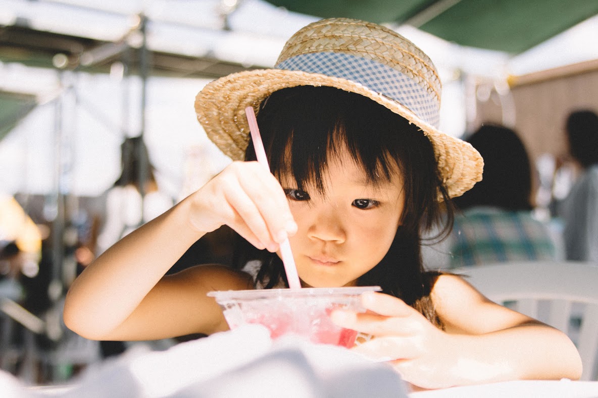 おいしそうにかき氷を食べている麦わら帽子の女の子