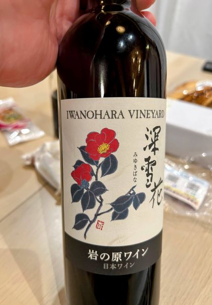 写真：深雪花（赤）のボトルラベル。陶芸家　齋藤三郎氏が描いた雪椿が印象的です。