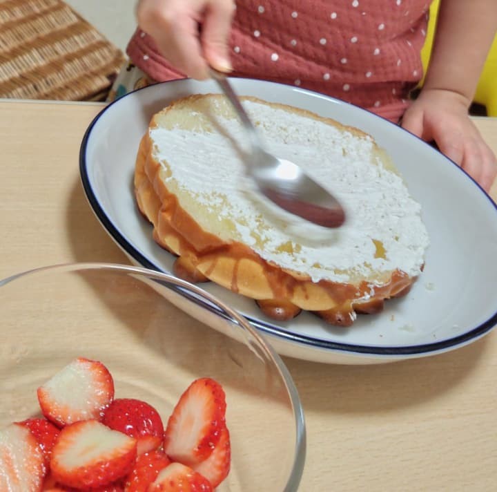 3の娘がスプーンでホイップクリームを塗っているところ