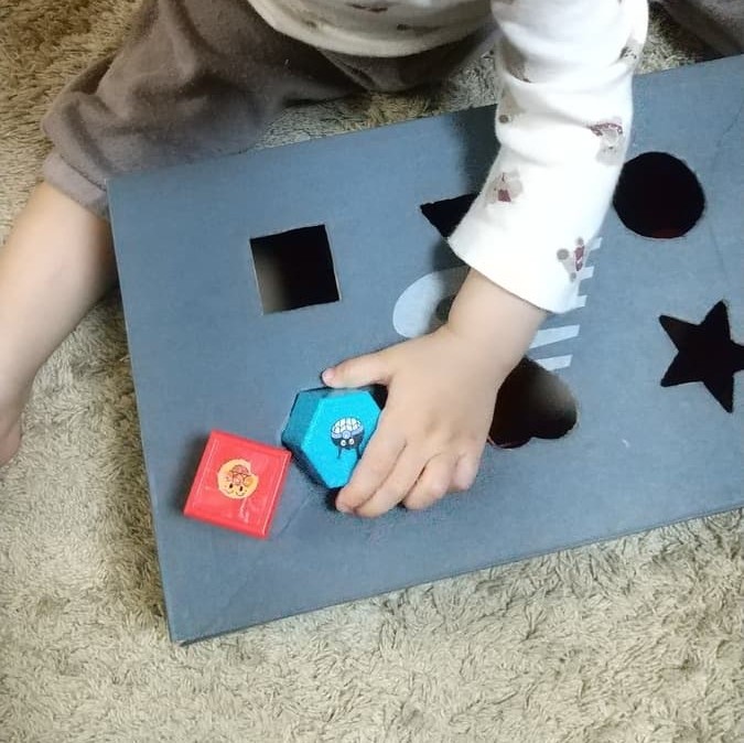 靴の空き箱で作った型はめパズルであそぶ様子