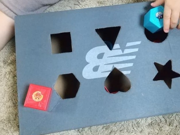靴の空き箱で作った型はめパズルであそぶ様子