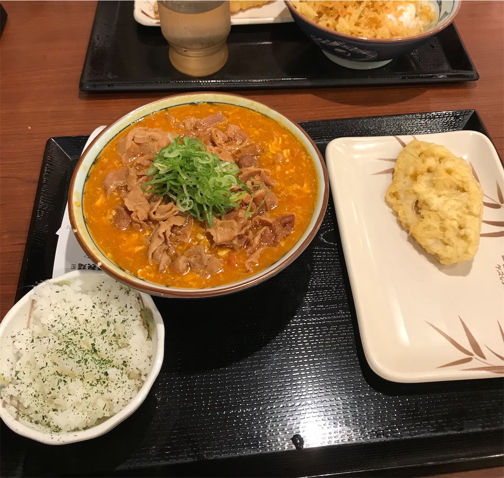 丸亀製麺のトマたまカレーうどん(豚肉入り)の並とれんこんの天ぷら(写真右)。