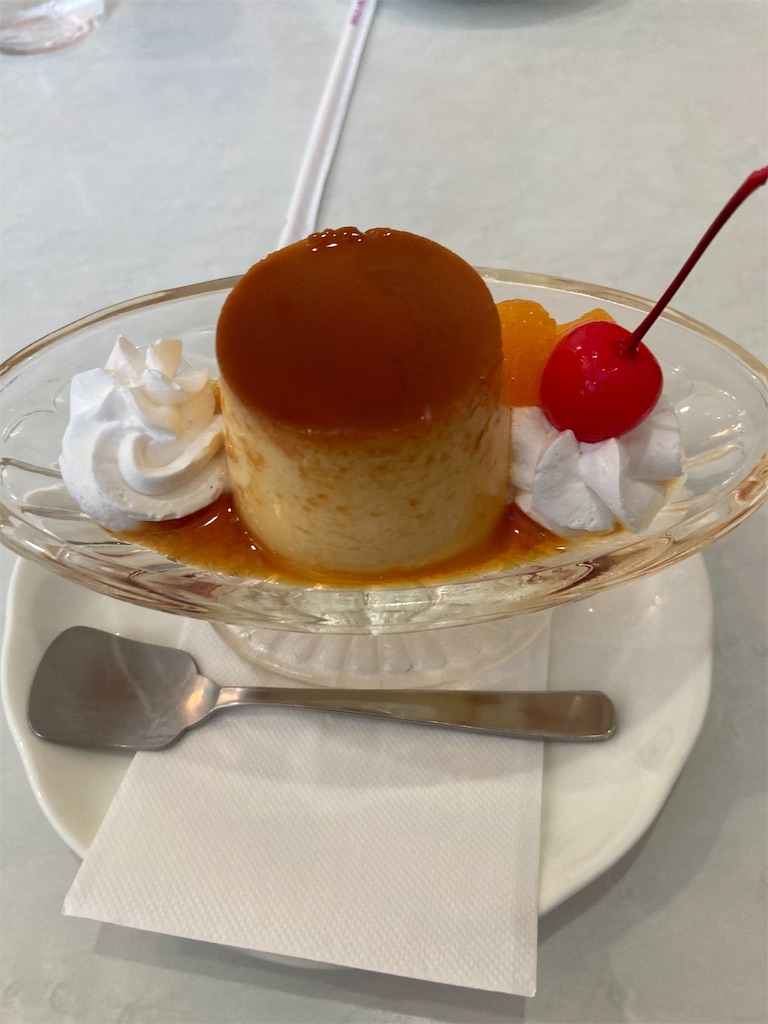 横浜第二合同庁舎の喫茶室で提供される固めのプリン。カラメルソースがたっぷりとかかり、ホイップクリーム、さくらんぼ、みかんが添えられている。