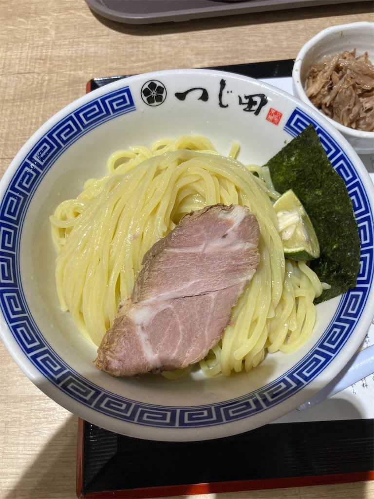 つじ田のつけ麺。もちもちとした麺の上に大きなチャーシューが乗っており、脇には海苔とすだちが添えられている。