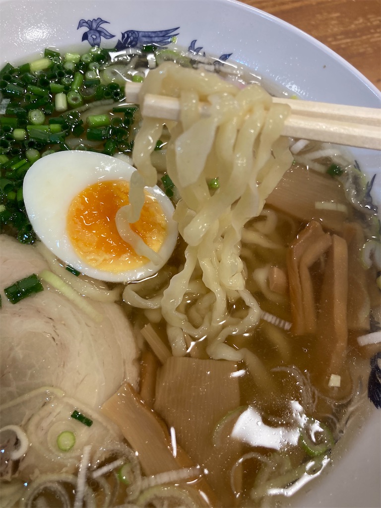 箸で持ち上げられたラーメンの縮れ麺。