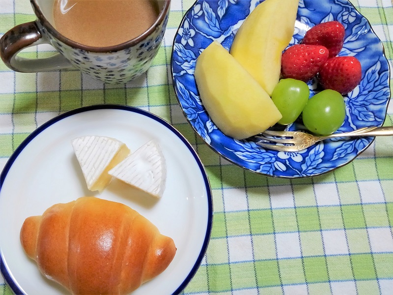 食卓に並べられたパン、カマンベールチーズ、フルーツとコーヒー