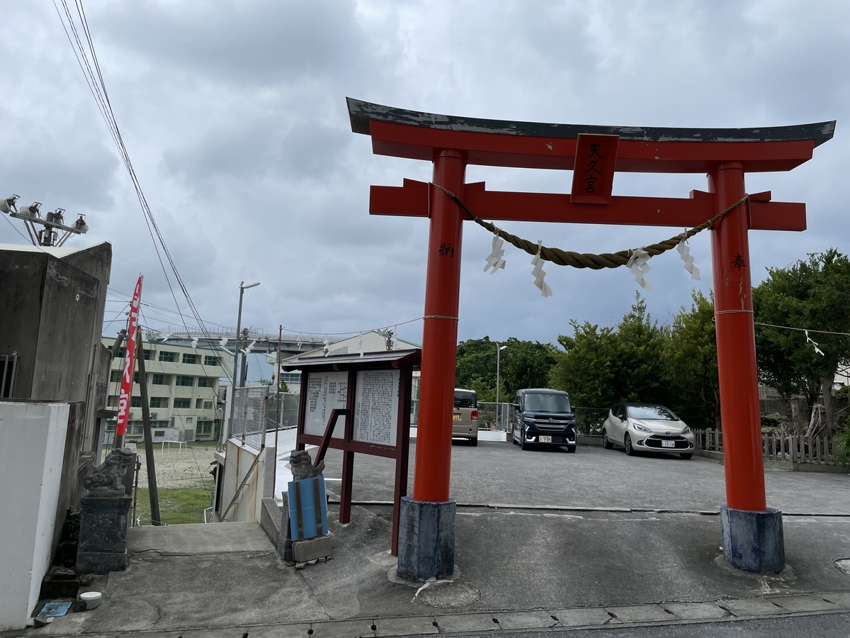 路地の入り口とその横に立つ鳥居、奥には駐車場