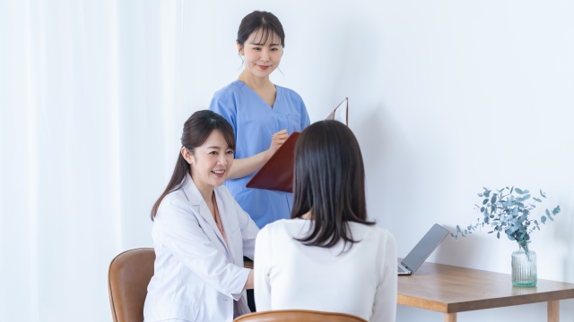 美容クリニックでの医師と看護師が女性患者にカウンセリングをしている様子