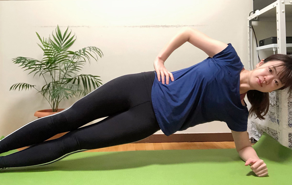 サイドプランク1。横向きになり、床側のひじを肩の下において上体を持ち上げる