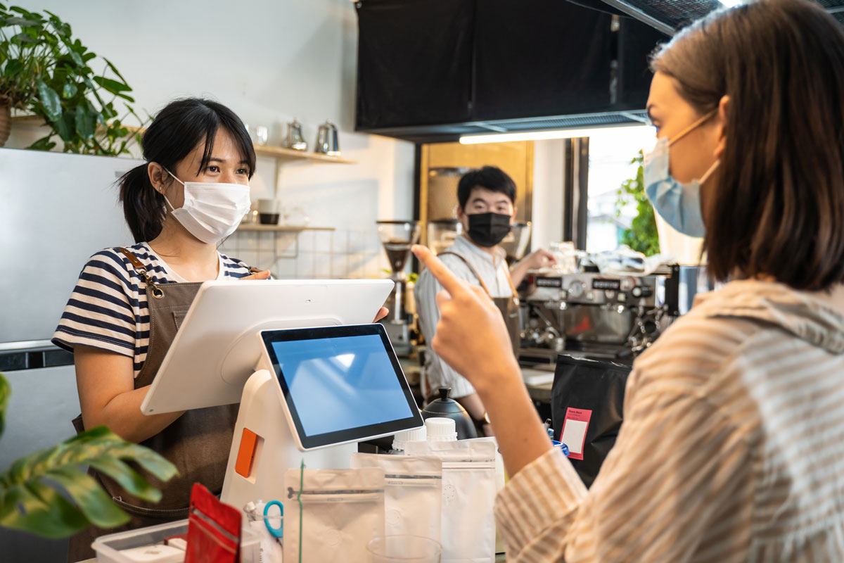 飲食店のレジ前で、店員とお客さんがやりとりしている写真