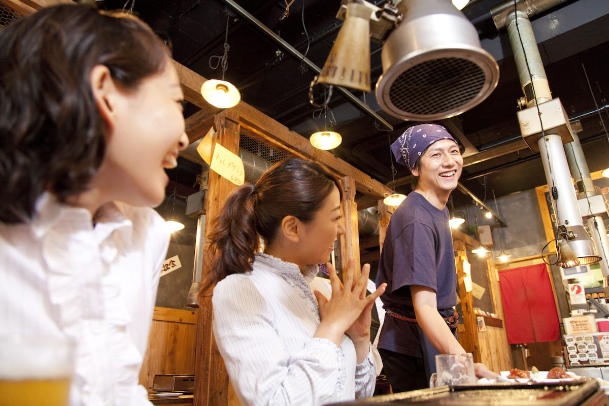 お客さん2人と笑顔で話している男性の店員