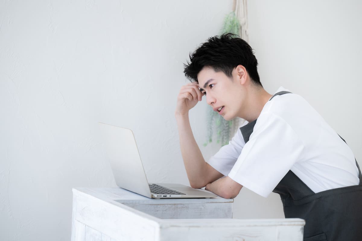 パソコンを見ながら悩んでいる飲食店店主