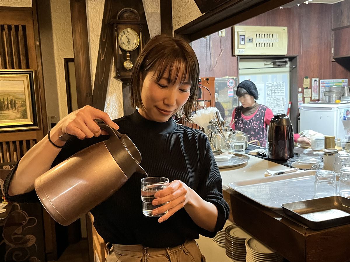 お冷を注ぐ大石さん。「こんなシーンを写真に撮られるのは初めてなので戸惑いますね」と言いつつ笑顔でご対応いただきました。ご協力感謝です!