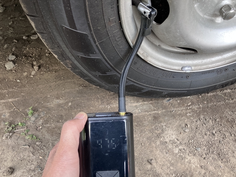 充電式空気入れでキャンピングカーのタイヤに空気を入れている様子