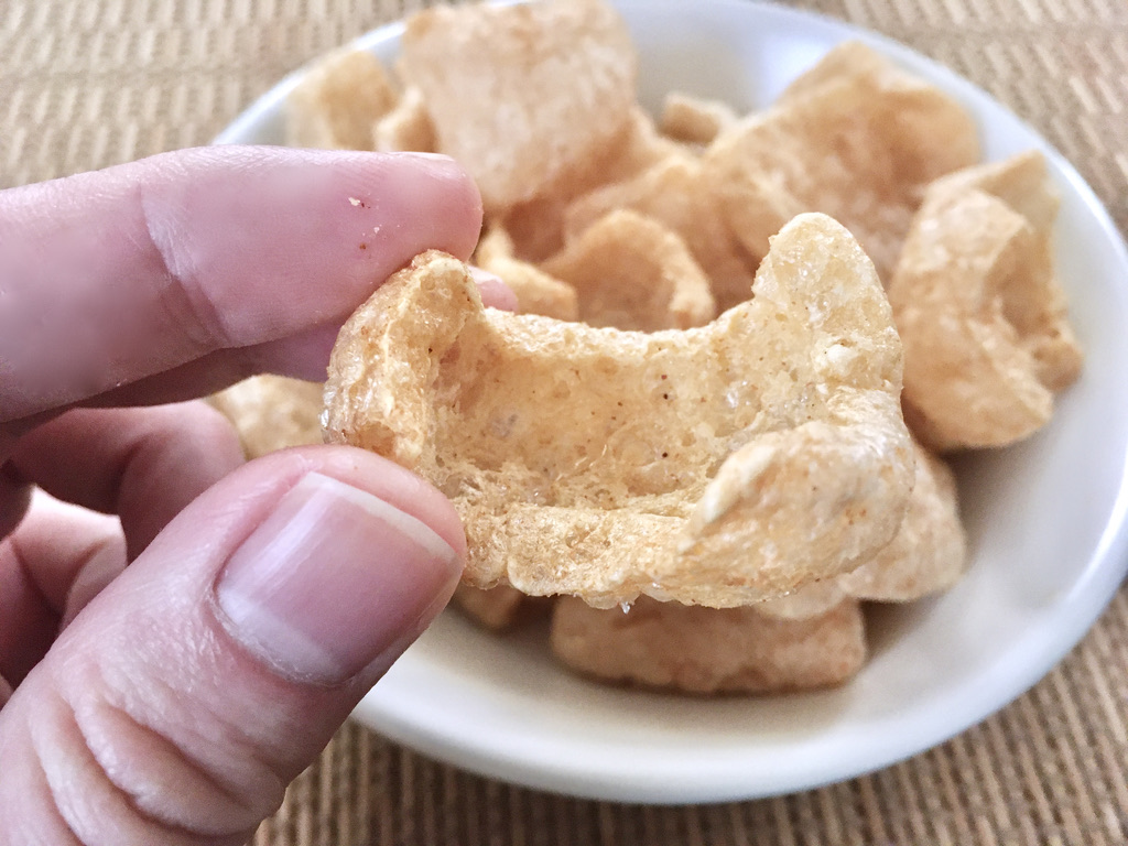 「豚皮揚げ（博多もつ鍋味）」を食べようとしているところ