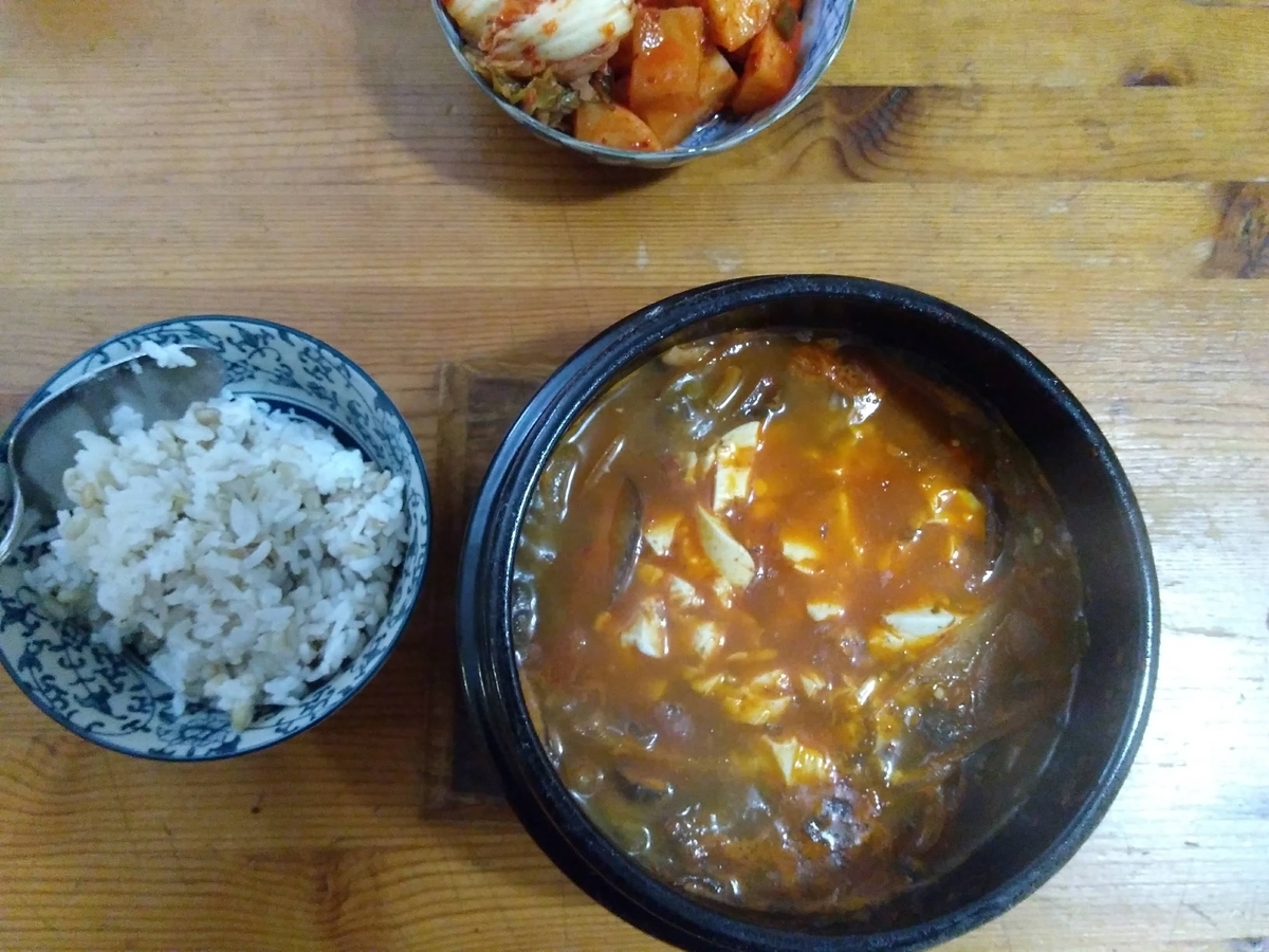 ヴィーガン純豆腐チゲ、麦入白米、キムチ、食卓に乗っている図