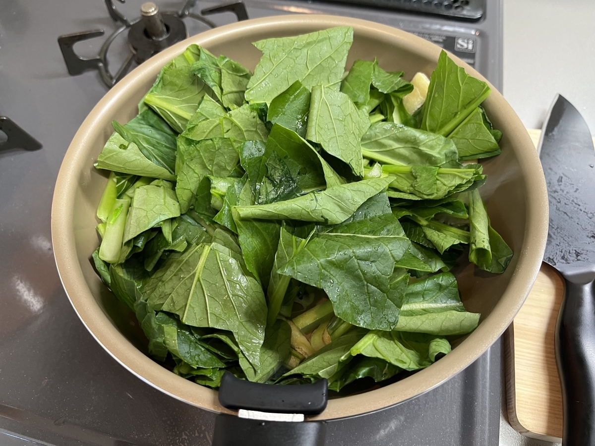 切った材料をフライパンに入れる。小松菜が多すぎてフライパンからはみ出しそうな写真