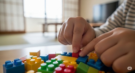 幼児の指先がブロックを精密に組み立てる様子、手先の巧緻性を高めるおもちゃ