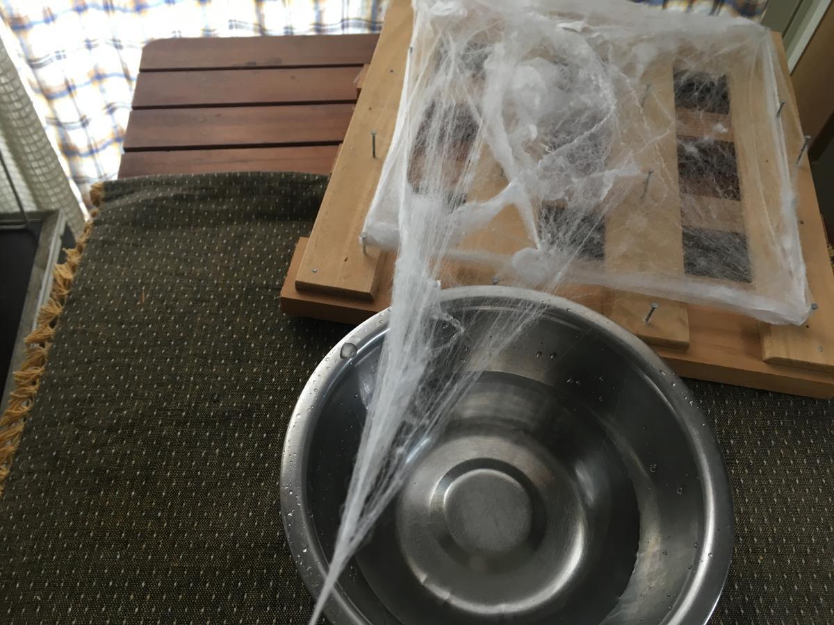 すのこの器具から真綿をひっぱって糸にする様子