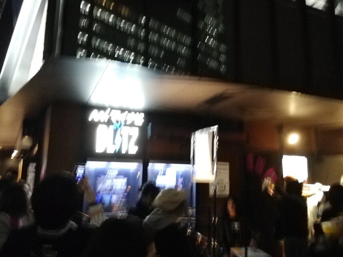 夜闇のなかで、ライブ会場である赤坂BLITZに貼られたライブポスターを撮影した写真だが、ひどくブレていてポスターは読み取れず、かろうじてBLITZの看板が読める程度になっている。
