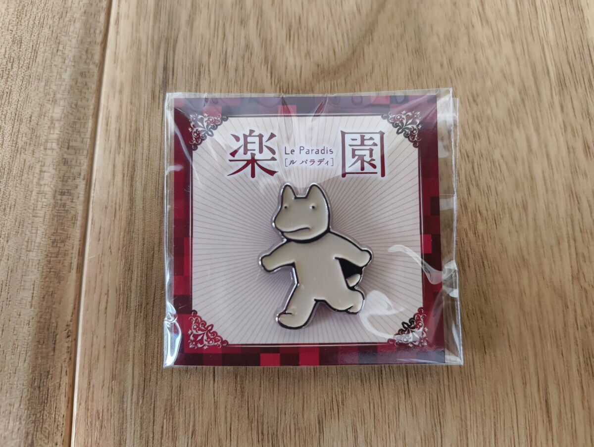 『楽園』と書かれた犬のピンバッジ
